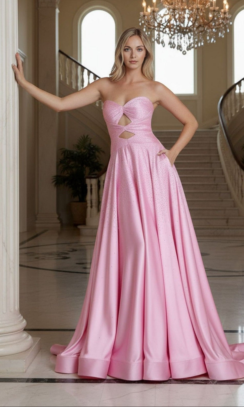 A woman poses indoors beside a column and grand staircase, wearing the Poly USA 25130 long pink prom dress with a strapless satin sweetheart neckline and two front cutouts, under a chandelier.